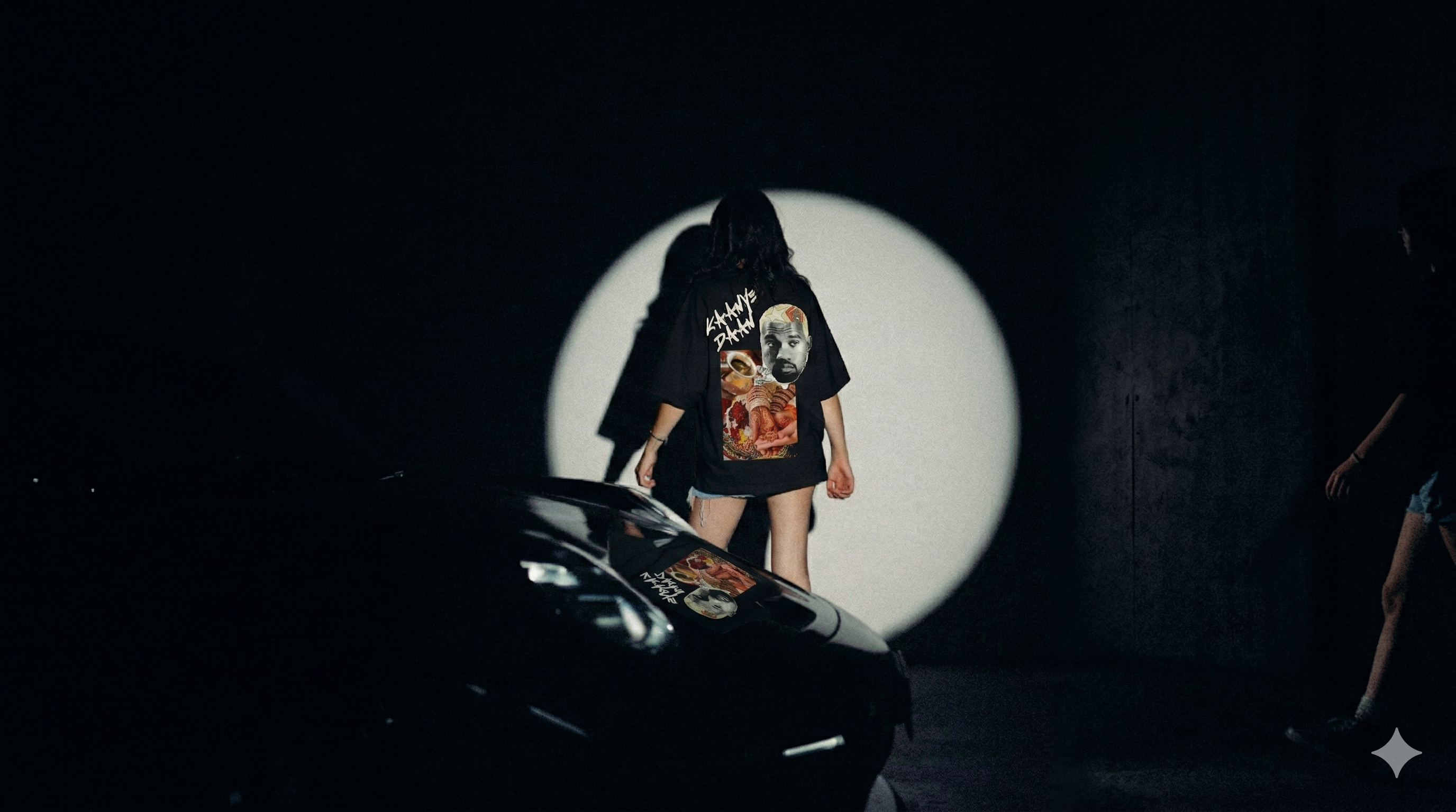 Person wearing a graphic t-shirt in front of a circular light source with a dark background